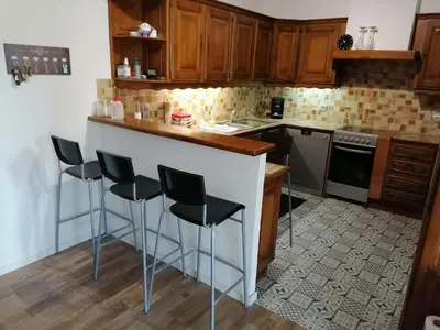 a kitchen with wooden cabinets and black bar stools at T3 proche de la mer in Portel-des-Corbières