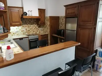 a kitchen with wooden cabinets and a counter with chairs at T3 proche de la mer in Portel-des-Corbières