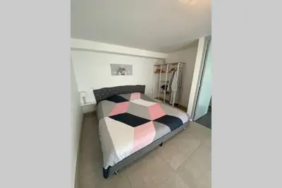 a bedroom with a bed with a pink and black comforter at Koh Samet Siam Manahakhon Appart & Spa in Rieux-de-Pelleport