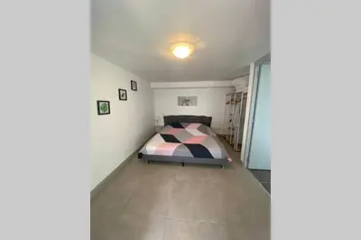 a bedroom with a bed in the corner of a room at Koh Samet Siam Manahakhon Appart & Spa in Rieux-de-Pelleport