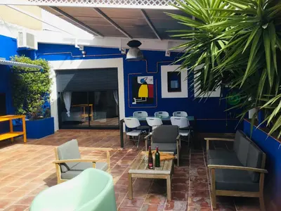 a patio with chairs and tables and a blue wall at Casa Léon in Narbonne
