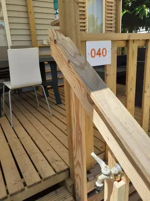 a wooden deck with a table and a chair at MOBILHOME agréable sans draps ni serviettes in Port-la-Nouvelle