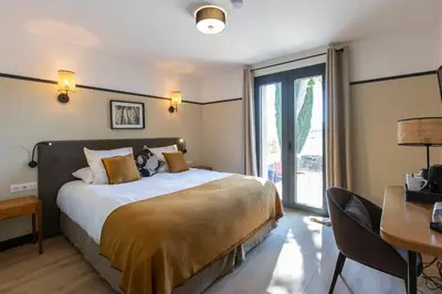 a bedroom with a bed and two chairs at Château de Lastours - Le Resort in Portel-des-Corbières