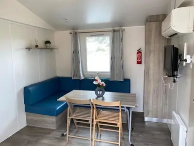 a dining room with a blue couch and a table and chairs at Le Solèou in Port-la-Nouvelle
