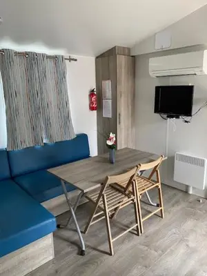 a living room with a table and a blue couch at Le Solèou in Port-la-Nouvelle