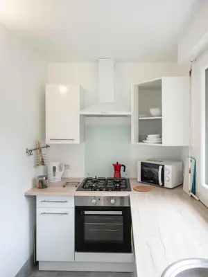 a kitchen with white cabinets and a stove top oven at Horizons Verts Appartement Cerisier in Puivert