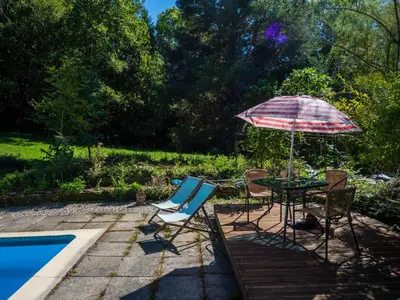 a table and chairs with an umbrella next to a pool at Horizons Verts Appartement Cerisier in Puivert