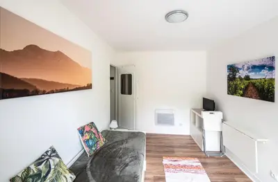 a living room with a couch and paintings on the wall at Horizons Verts Appartement Cerisier in Puivert