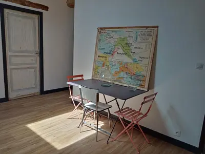 a table with chairs and a map on a wall at Une perle dans la malepère. in Montréal