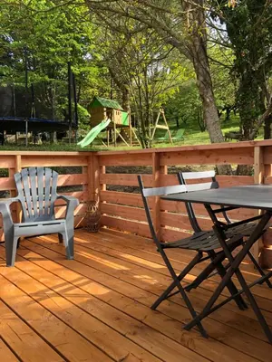 a table and chairs on a deck with a playground at Fanjeaux Aude Le Chalet in Fanjeaux