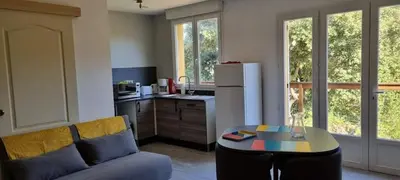 a living room with a couch and a table and a kitchen at La petite étape in Duilhac