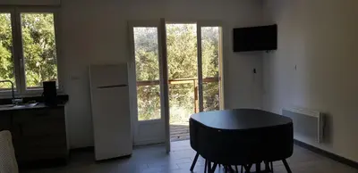 a kitchen with a table and a refrigerator and a window at La petite étape in Duilhac