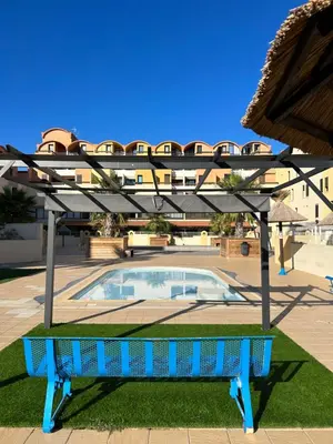 a blue bench in front of a swimming pool at Les Drom's studio in Gruissan