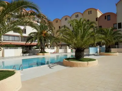 a courtyard with a swimming pool with palm trees at La Brigantine in Gruissan