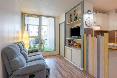 a living room with a couch and a clock on a wall at La Brigantine in Gruissan