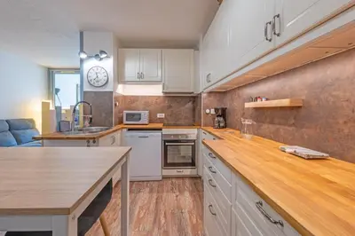 a kitchen with white cabinets and a wooden counter top at La Brigantine in Gruissan