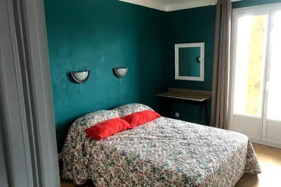 a green bedroom with a bed with a red pillow at Grands Buffets hébergement Appartement Narbonne in Narbonne