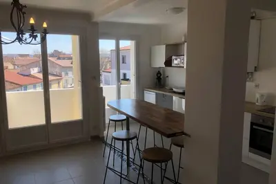 a kitchen with a wooden table and stools at Grands Buffets hébergement Appartement Narbonne in Narbonne