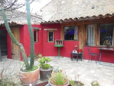 a red house with a patio with a table and chairs at maison dans jardin in Villesèque-des-Corbières