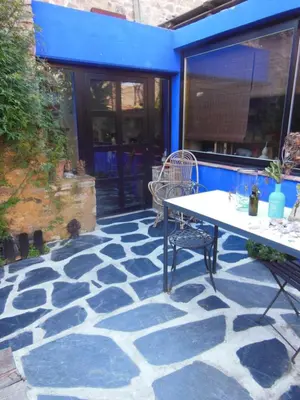 a patio with a table and chairs on a stone floor at maison dans jardin in Villesèque-des-Corbières