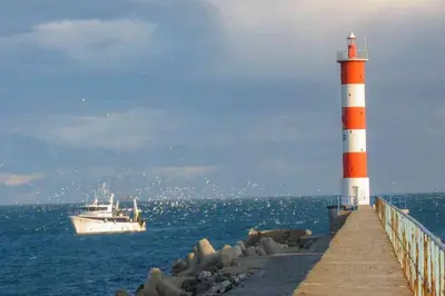 a boat on the water next to a lighthouse at Mobil home 5-6 personnes - climatisé in Port-la-Nouvelle