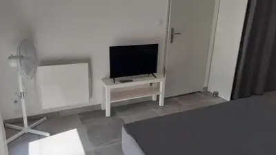 a living room with a couch and a television at Le Logis des 3 Moulins in Sigean