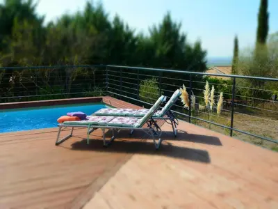 a chair on a deck next to a swimming pool at Villa with Pool & Views in Oupia