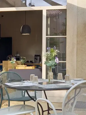 a table with chairs and a vase with flowers on it at La Maison de Gruissan in Gruissan