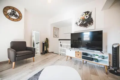 a living room with a large television and a chair at La cathédrale à portée de main ! in Narbonne
