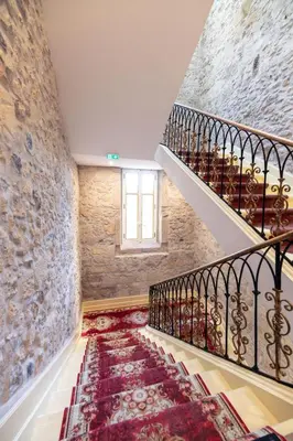a staircase in a building with a stone wall at Suite Royale Maison de l'église du couvent in Narbonne