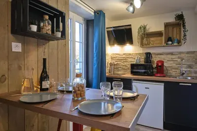 a kitchen with a wooden table with plates and wine glasses at Chez Juliette - Appart & Studios - Carcassonne centre in Carcassonne