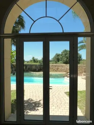 an open glass door with a view of a pool at Chambres d'hôtes la Soulenque Luxury B & B in Capestang