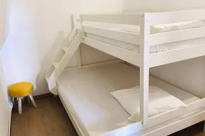 a white bunk bed with a yellow stool in a room at Résidence Port Soleil Duplex T3 46 m2 climatisé in Gruissan