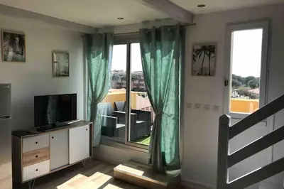 a living room with a television and a large window at Résidence Port Soleil Duplex T3 46 m2 climatisé in Gruissan