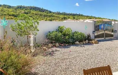 a garden with a bench in front of a wall at 2 Bedroom Cozy Home In Saint Chinian in Saint-Chinian