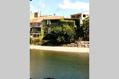 a house on a beach next to a body of water at Character filled house overlooking the River Cesse in Bize-Minervois