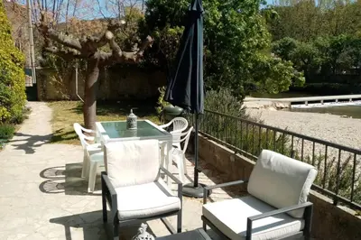 a patio with a table and chairs and an umbrella at Character filled house overlooking the River Cesse in Bize-Minervois