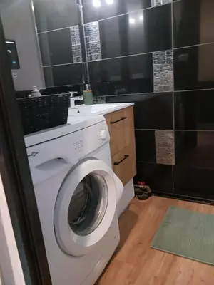 a white washing machine in a bathroom with black tiles at Cocoon'House in Gruissan