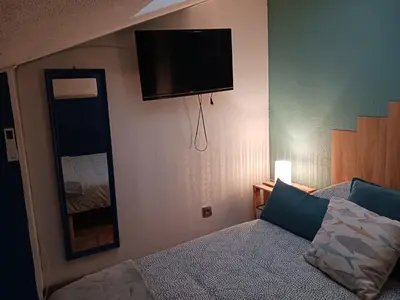 a bedroom with a bed and a flat screen tv on the wall at Cocoon'House in Gruissan