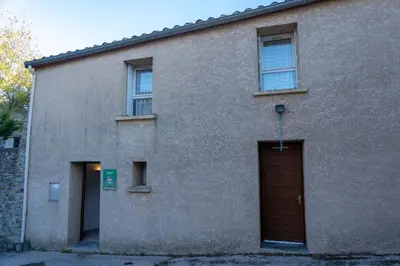 a building with a brown door and two windows at Gîte Mairie in Fosse
