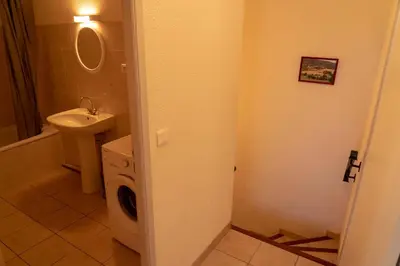 a bathroom with a sink and a washing machine at Gîte La Place in Fosse