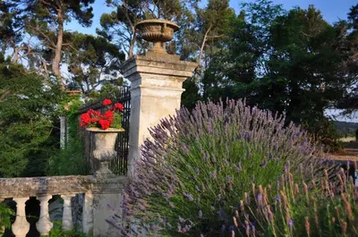 a stone fence with a vase with flowers on it at Château De Massignan in Saint-Marcel