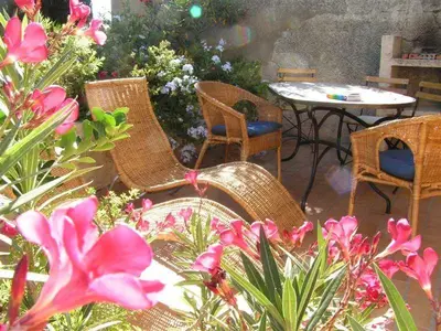 a patio with wicker chairs and tables and flowers at Château De Massignan in Saint-Marcel