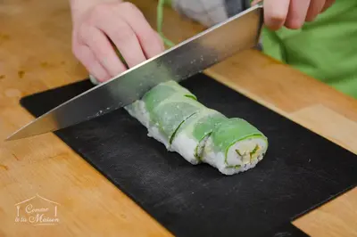 a person cutting a piece of sushi with a knife at COMME A LA MAISON in Espéraza