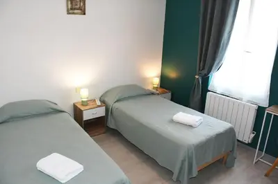 two beds in a room with green walls and a window at COMME A LA MAISON in Espéraza