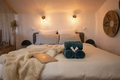 a bedroom with a bed with a laptop and roses at Le Boheme - Netflix - Wifi - Vue sur la Cité Médiévale et les toits in Carcassonne