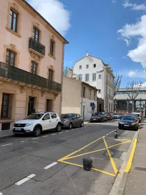 a city street with cars parked in a parking lot at LE CORS’HALLES in Narbonne