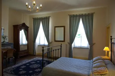 a bedroom with a bed and two windows at L'Impasse du Temple in Léran