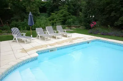 a pool with chairs and an umbrella next to it at L'Impasse du Temple in Léran