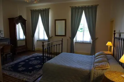 a bedroom with a bed and two windows at L'Impasse du Temple in Léran